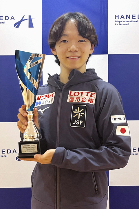 トロフィーを手に撮影に応じるフィギュアスケート男子の鍵山優真=16日、羽田空港